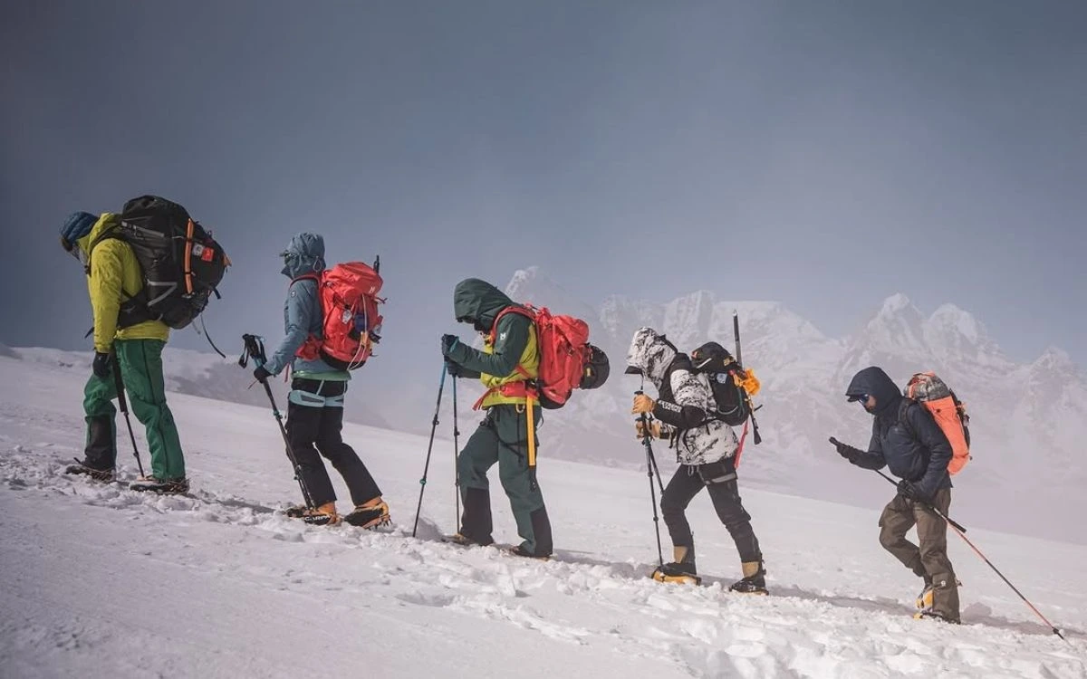 A small group of trekkers hiking an alpine trail with mountain guides